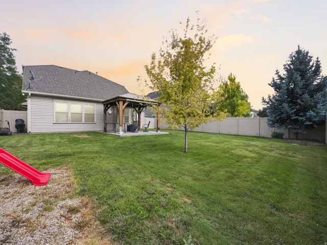 Expansive grassy lawn with a covered patio featuring a wooden pergola