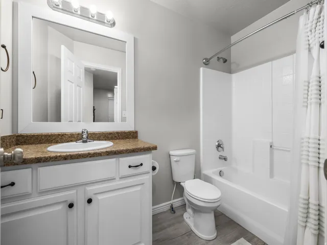 White vanity with dark hardware, a brown countertop, and an undermount sink