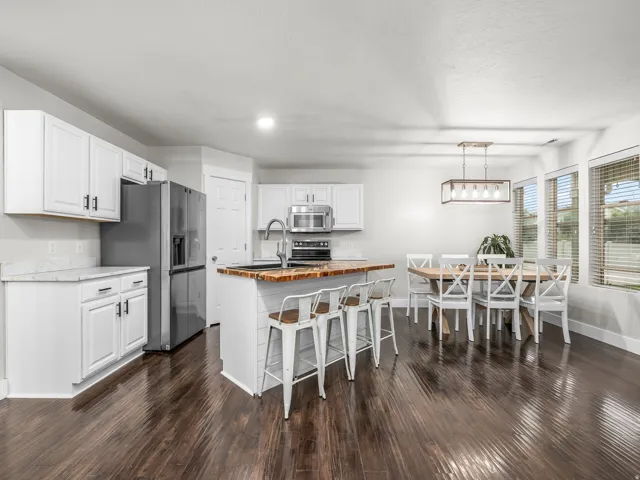 Open-concept kitchen featuring white cabinetry, stainless steel appliances, and wood-finish flooring
