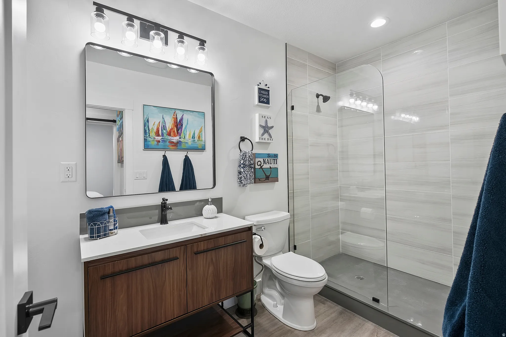 Contemporary vanity with a rectangular basin sink, wood-finish cabinetry, and matte black hardware