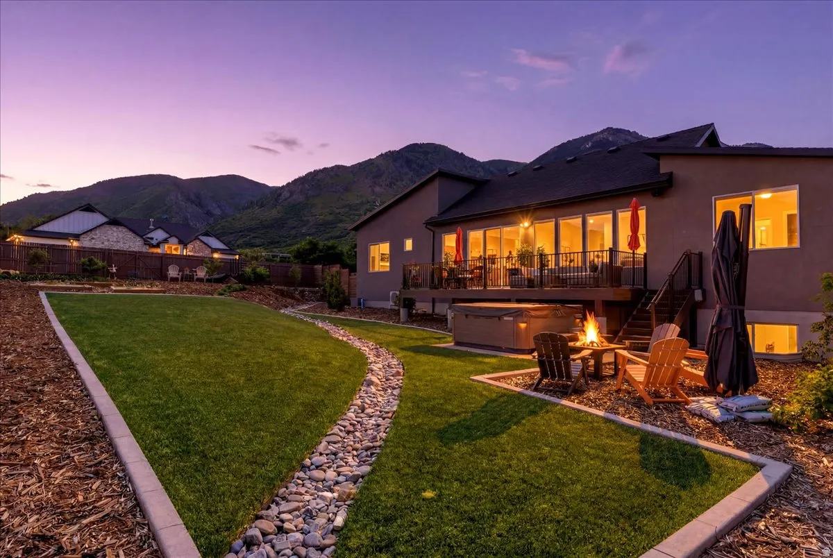 Expansive backyard featuring a manicured lawn, rock-lined dry creek bed, and a built-in hot tub