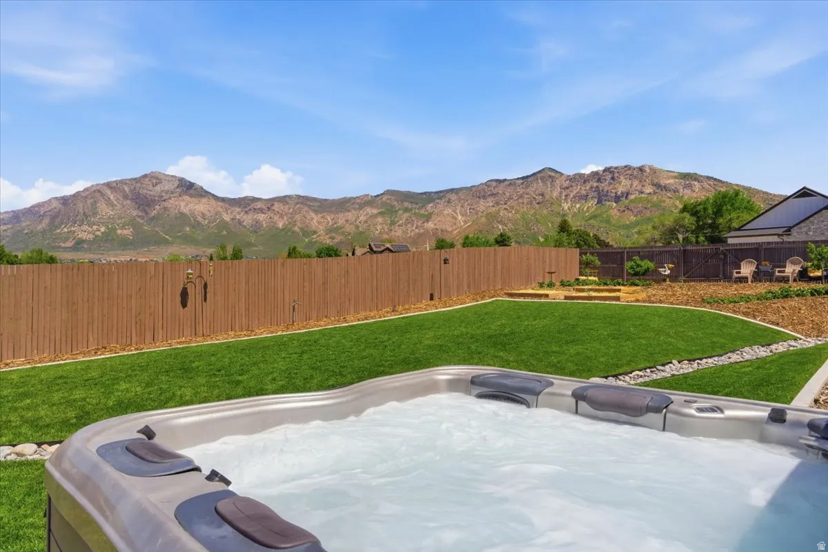 Built-in spa, expansive manicured lawn, established privacy fencing, terraced landscaping, and prominent mountain backdrop