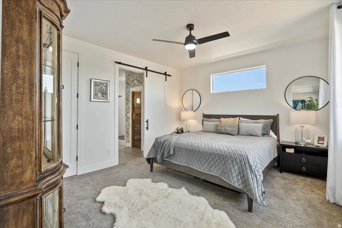 Barn door entrance, transom window, recessed lighting, ceiling fan, carpeted flooring