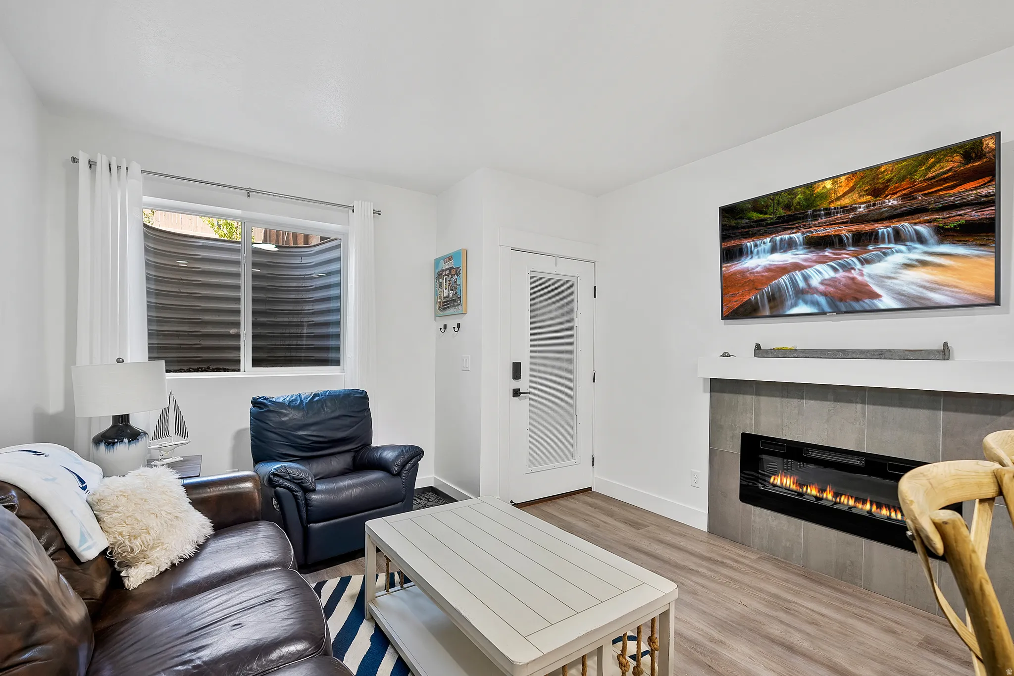 Recessed electric fireplace with a tiled surround, wood-finish flooring, and white wall finishes