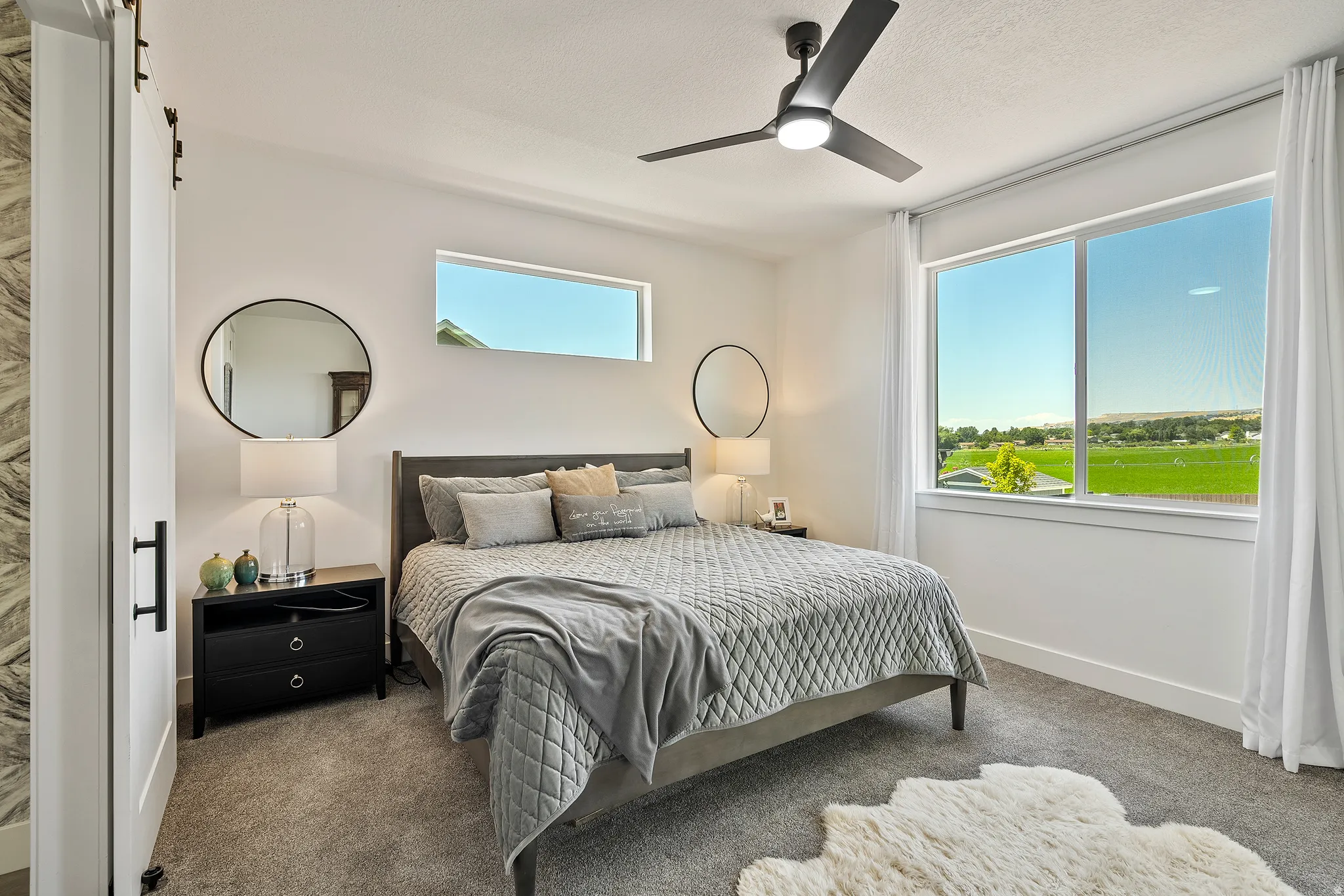 Recessed ceiling light with a ceiling fan, a prominent window, a horizontal transom window, and a white barn door with black hardware