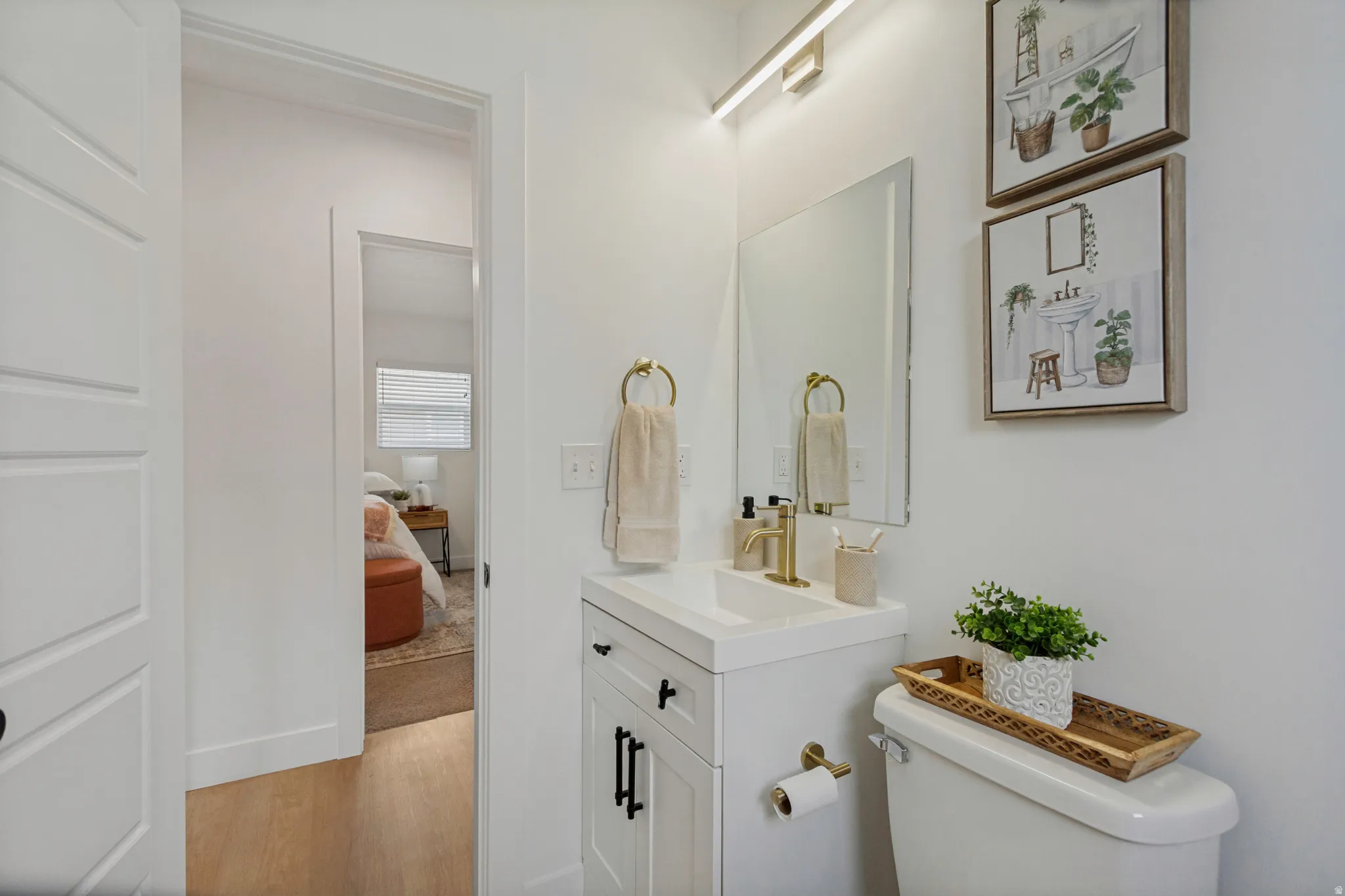 White vanity with integrated sink, brass-finish faucet, and coordinating mirror