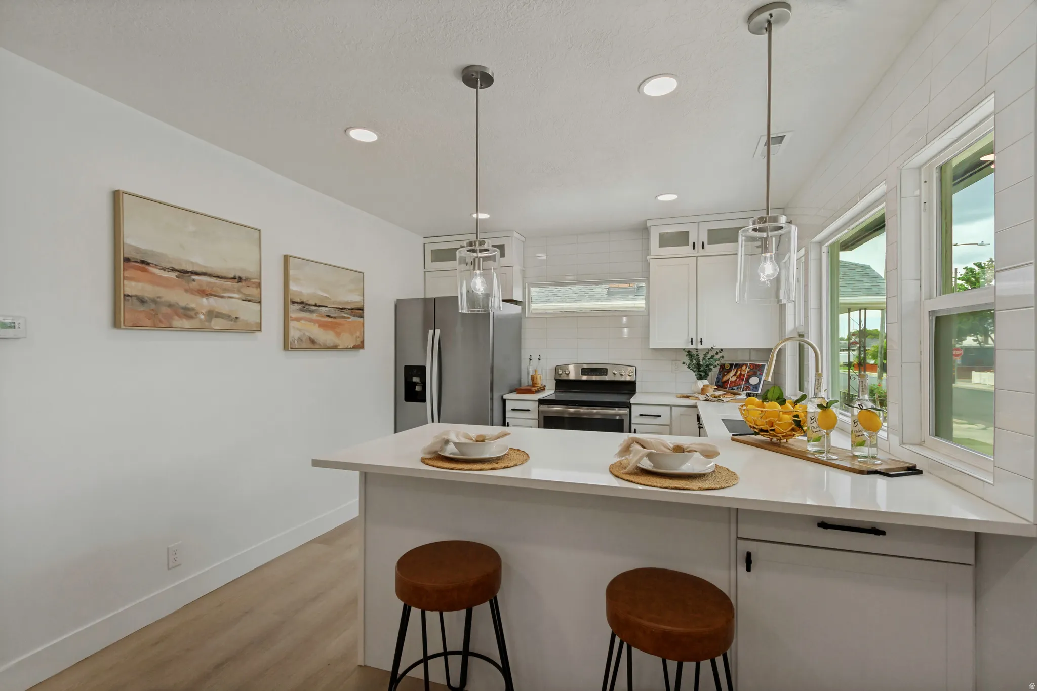 Kitchen featuring white cabinetry, stainless steel appliances, pendant lighting, wood-finish flooring, and a window above the sink