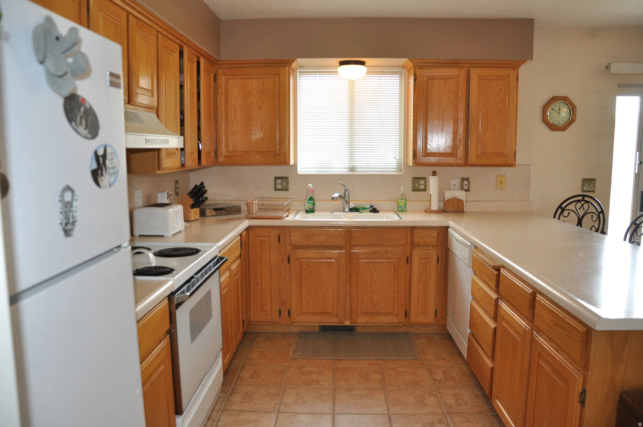 U-shaped kitchen featuring wood-finish cabinetry, tile flooring, and light-toned countertops