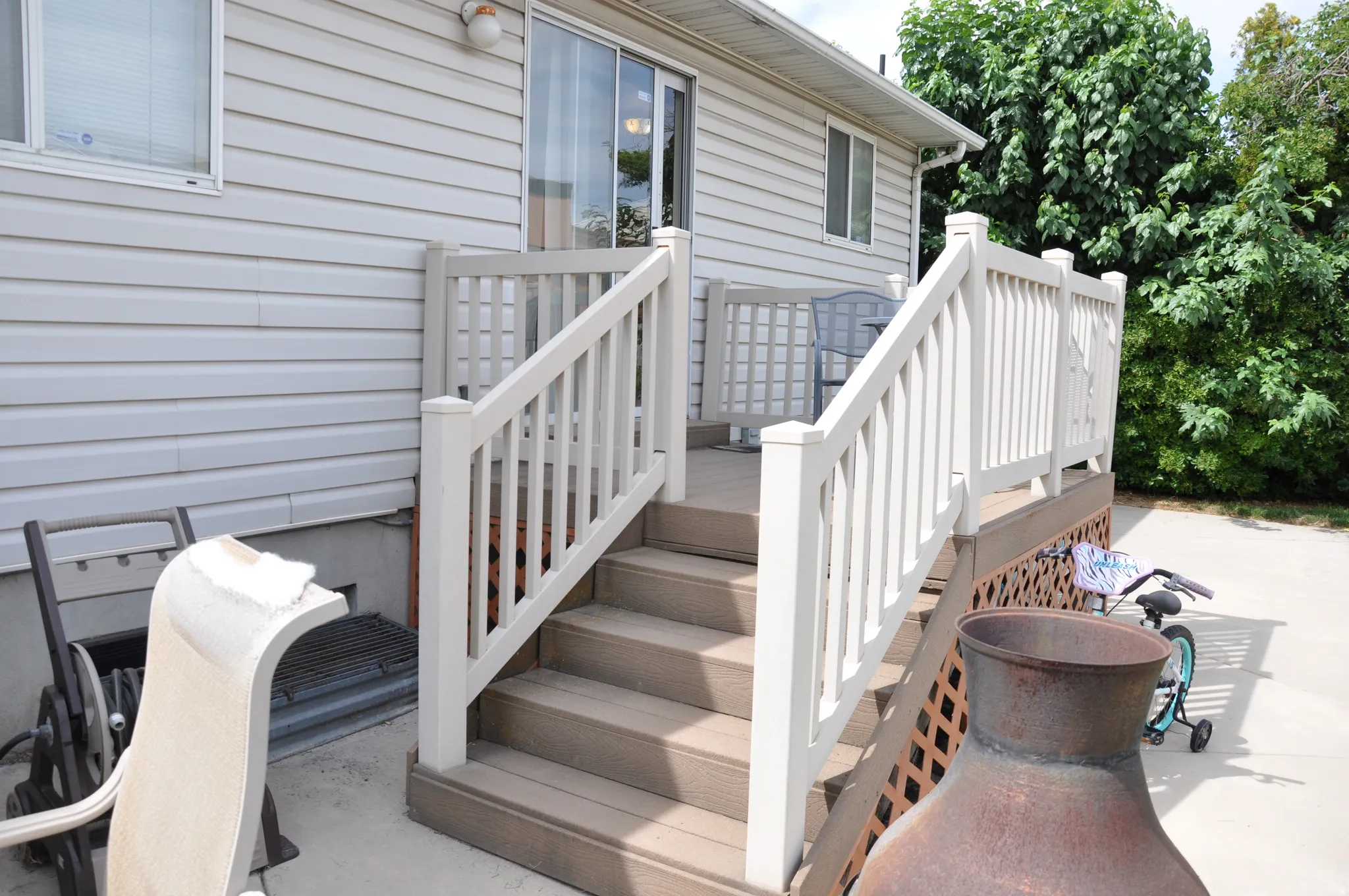 Exterior siding with a built-in deck featuring composite steps and white railings