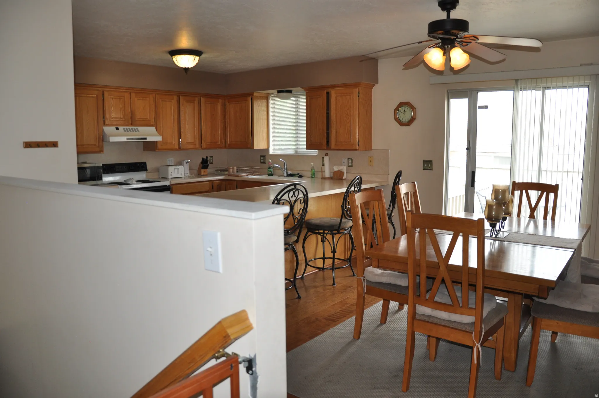 Kitchen and dining area featuring wood-finish cabinetry, a ceiling fan with integrated lighting, and a sliding glass door