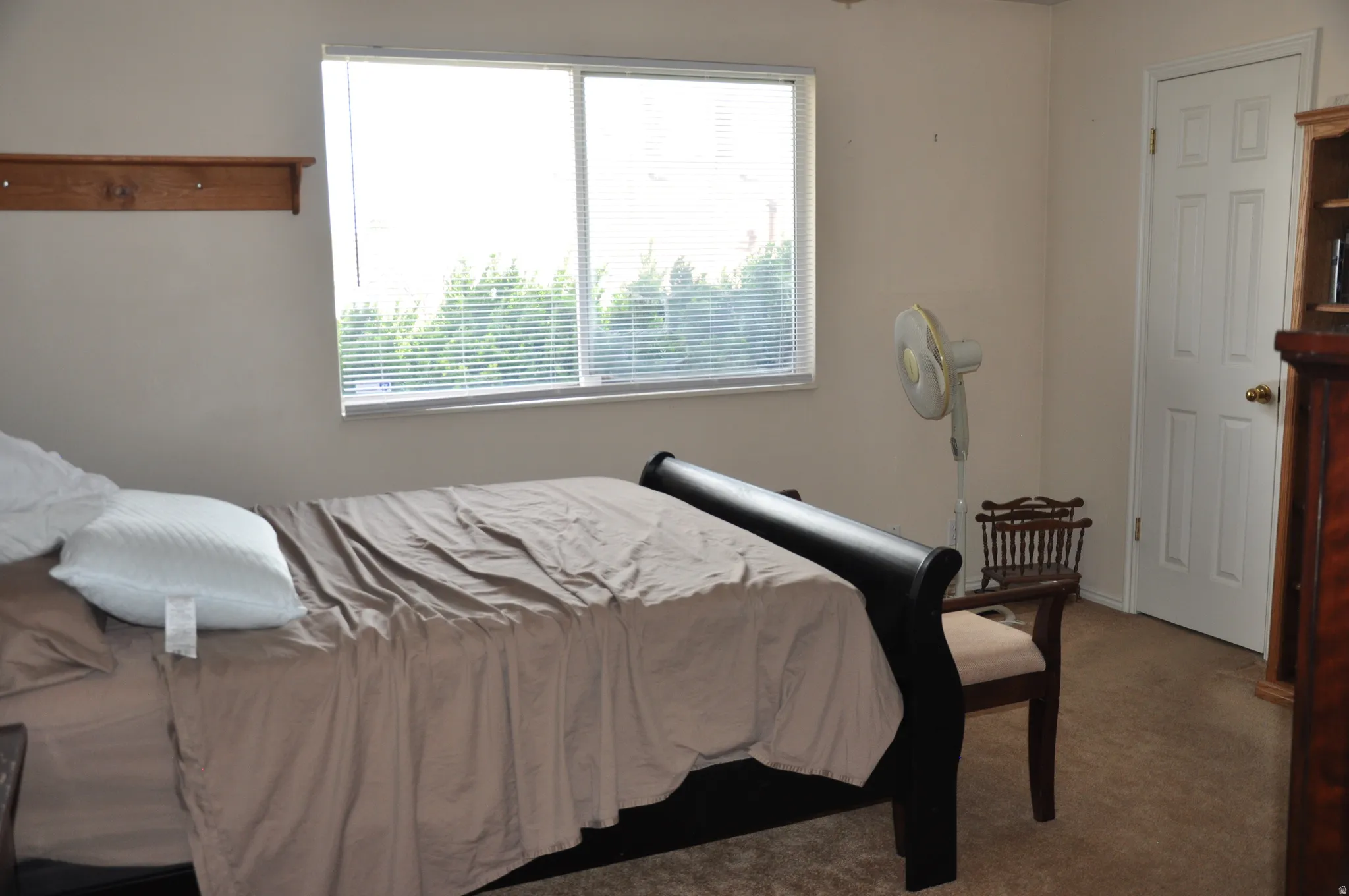 Window with horizontal blinds, wood wall shelf, and paneled door