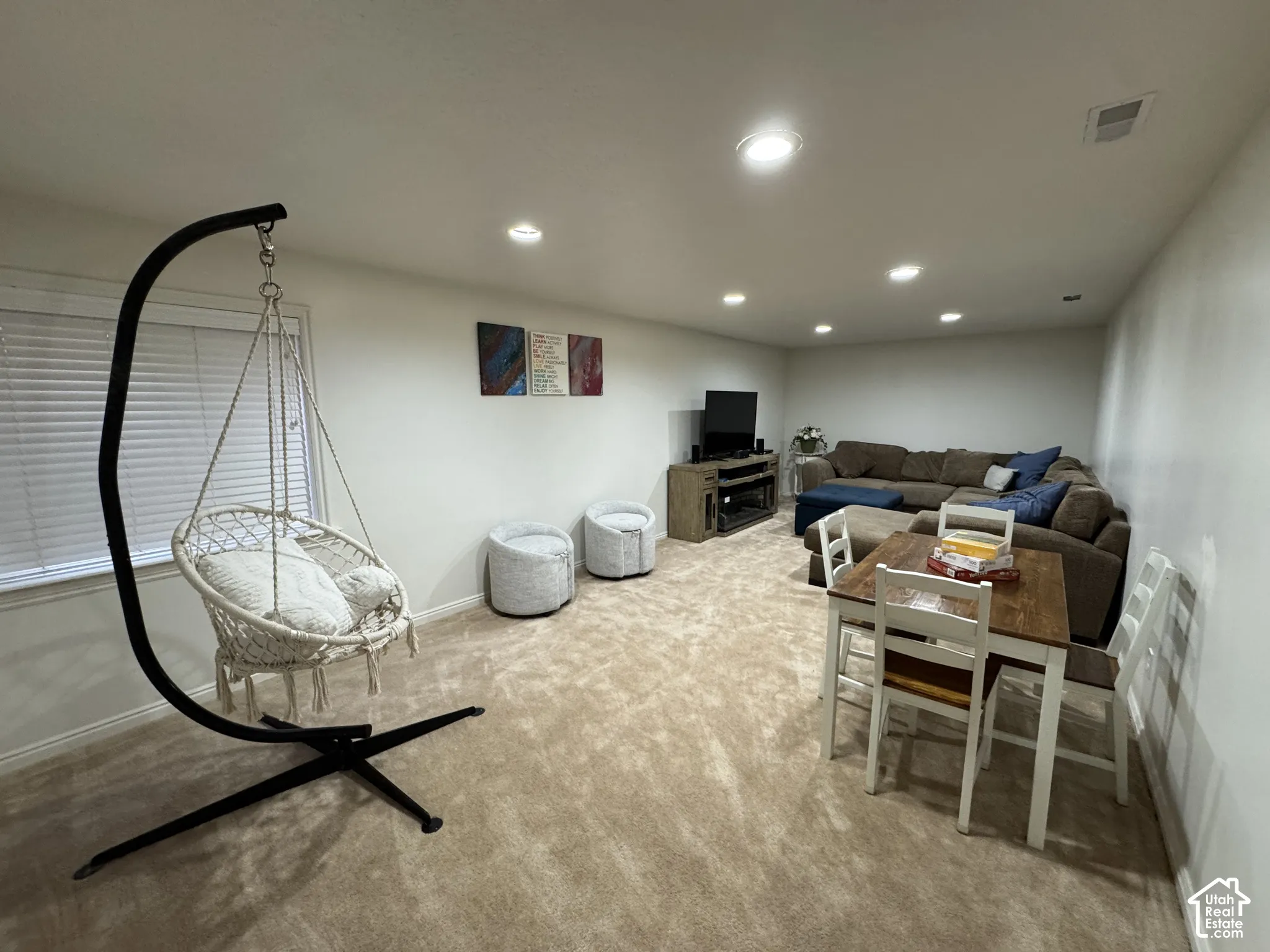 This basement family room is large enough to swing, watch movies and play games all at the same time.  It offers recessed lighting with dimmers, light-colored carpeting, and a window with horizontal blinds