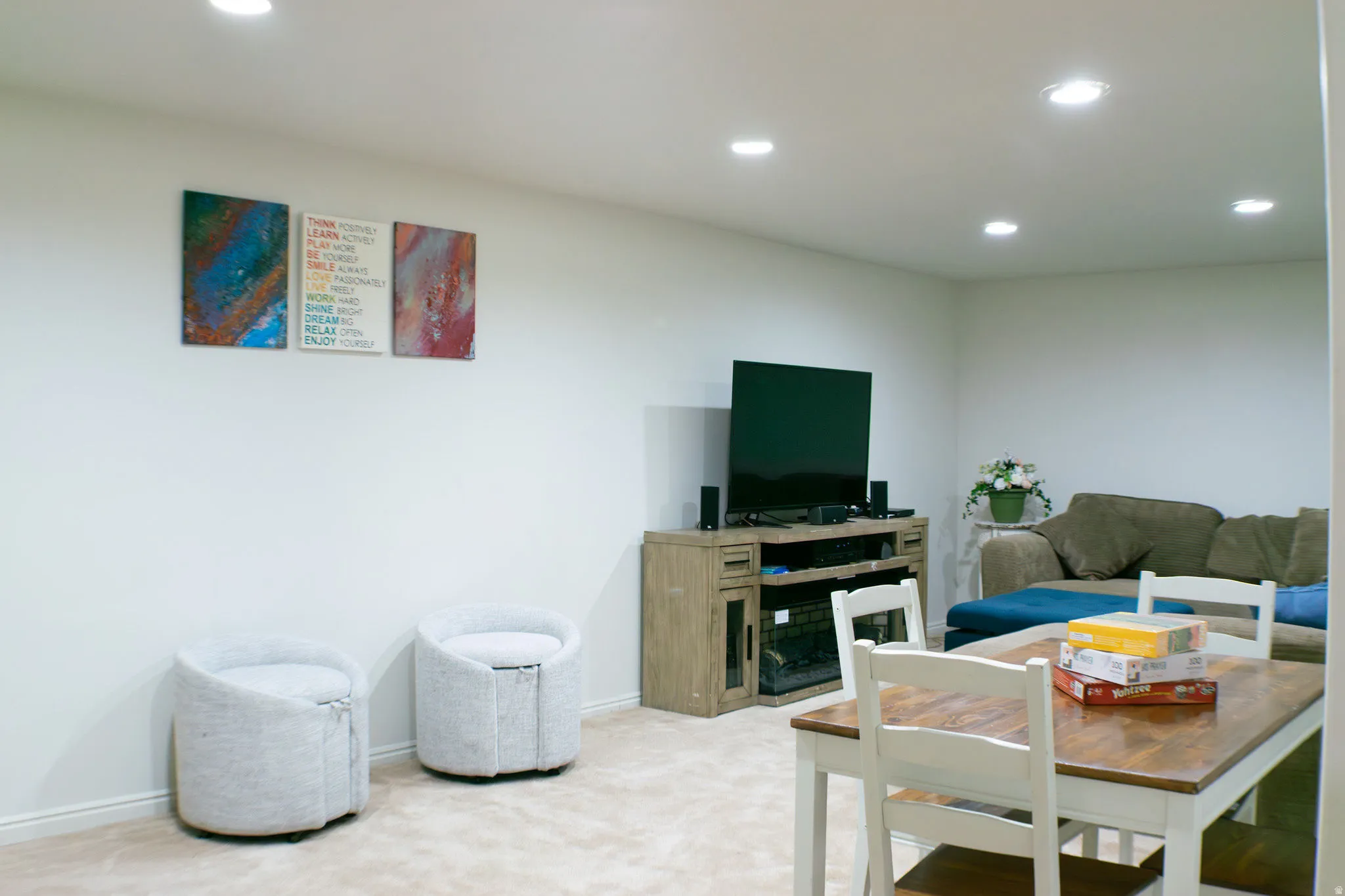 Recessed lighting illuminating a carpeted living space with a wood-finish media console