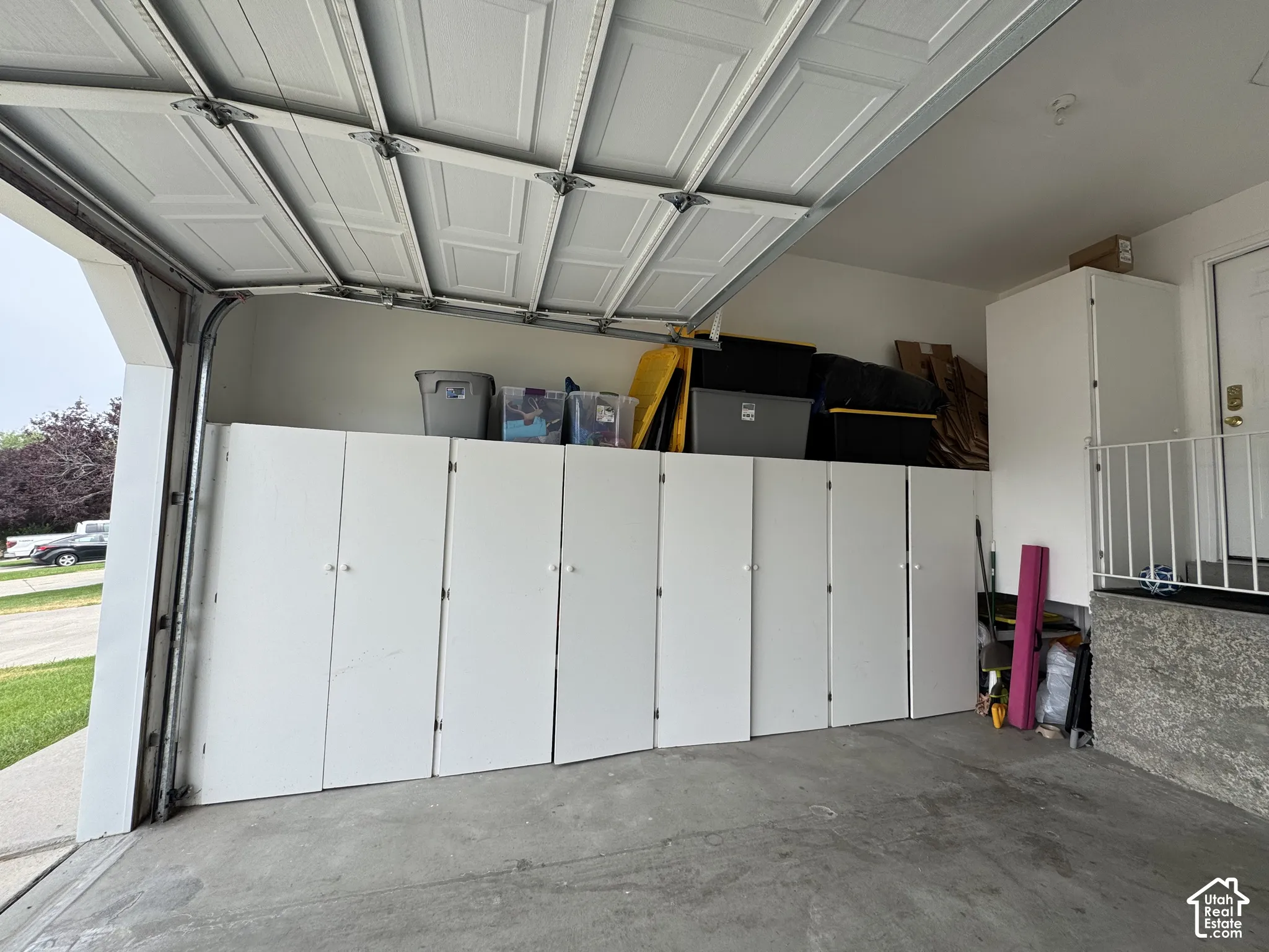 Built-in white cabinetry, concrete flooring, and an overhead garage door