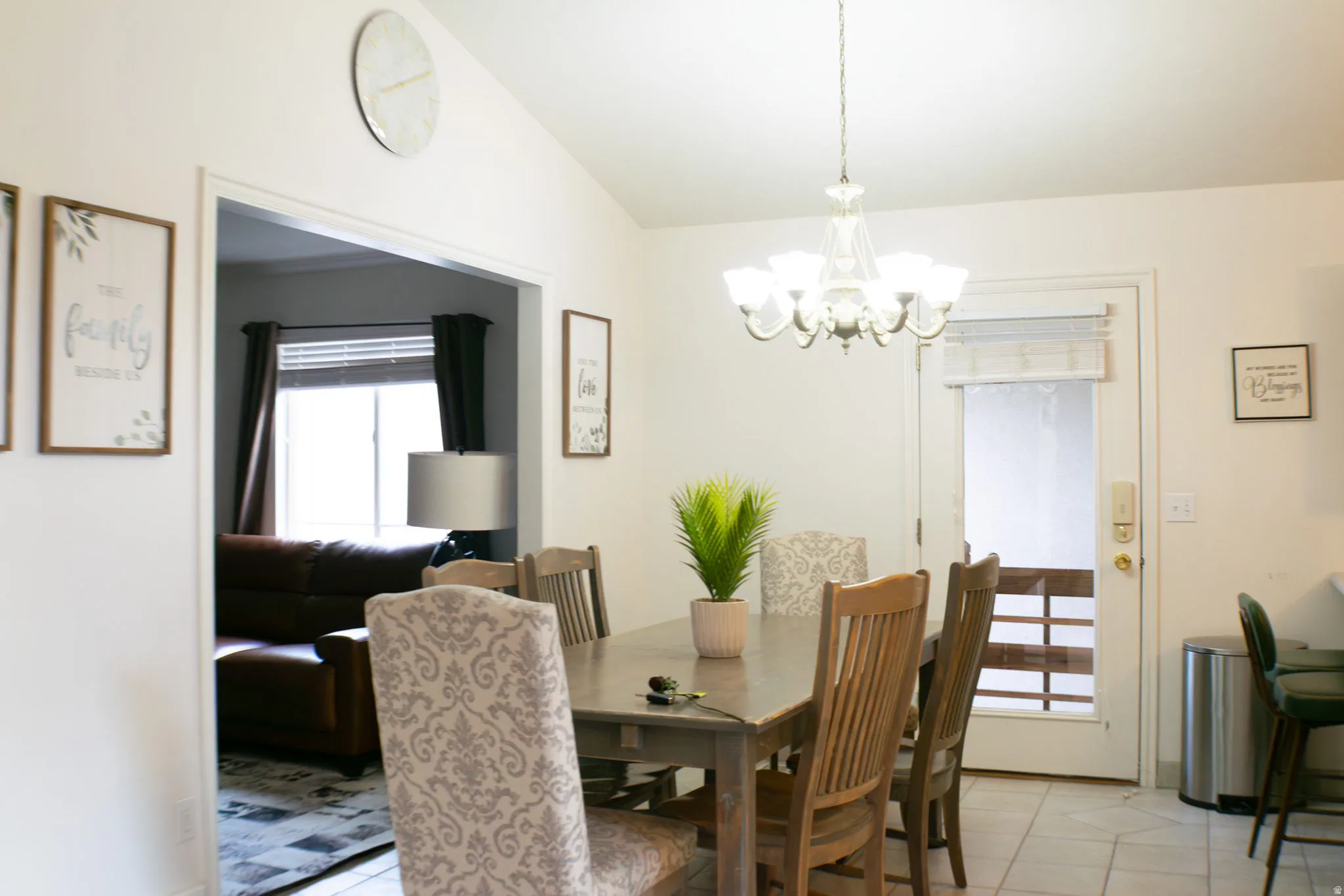 Vaulted ceilings with a chandelier light fixture, featuring a white paneled door with glass inserts, and tile flooring