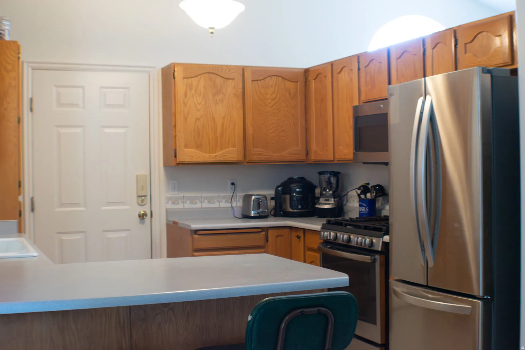 Kitchen featuring stainless steel appliances, wood cabinetry, and a breakfast bar