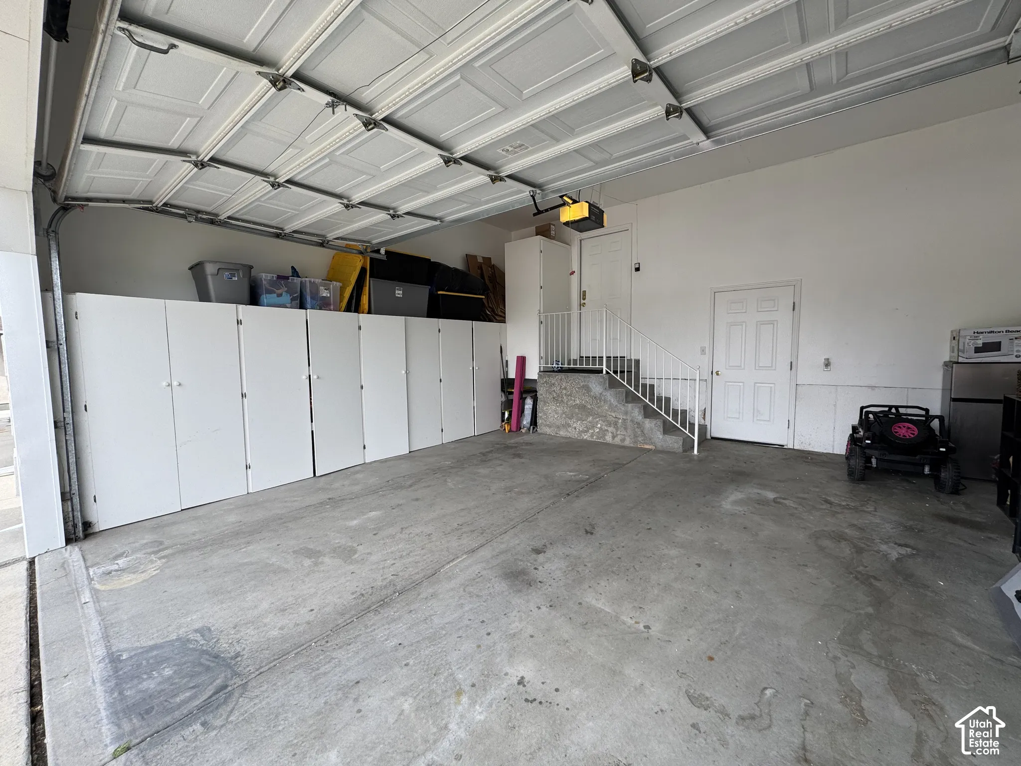 Built-in cabinetry, interior access door, concrete flooring, and an automatic garage door opener