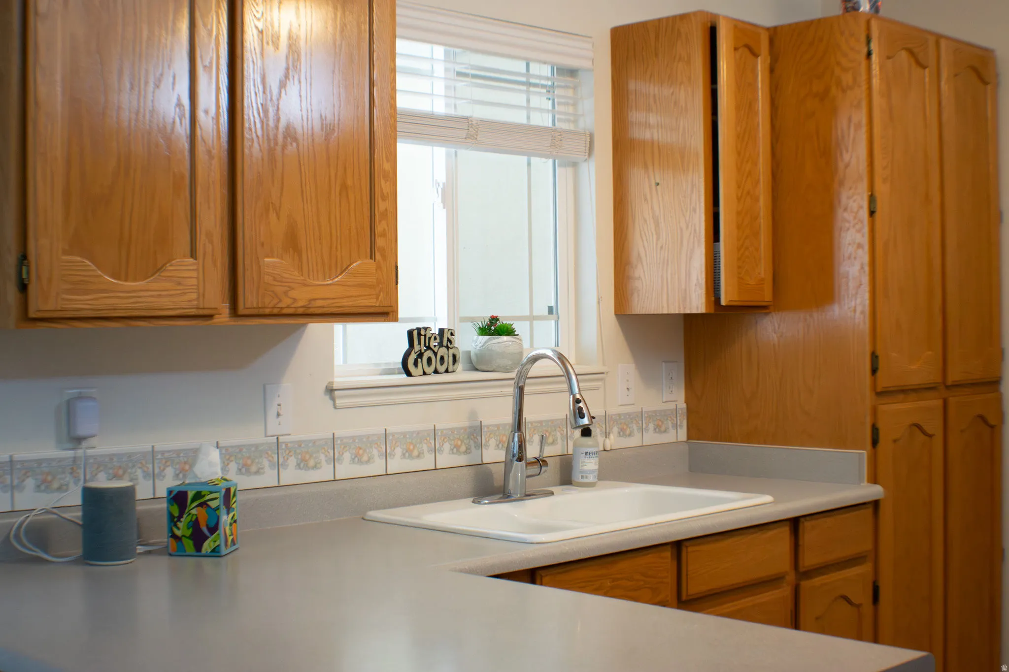 Kitchen featuring light wood-finish cabinetry, light countertops, and a decorative tile backsplash