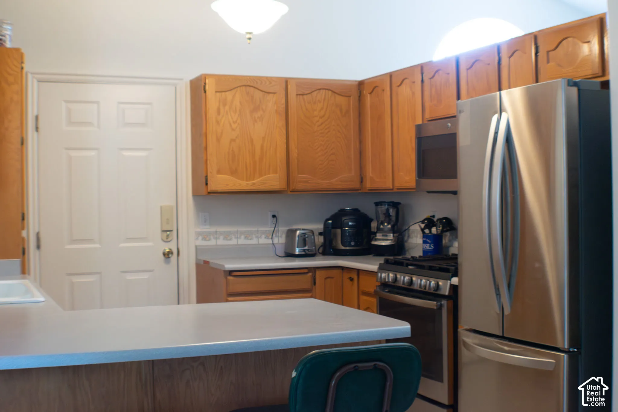Kitchen featuring stainless steel appliances, wood cabinetry, and a breakfast bar