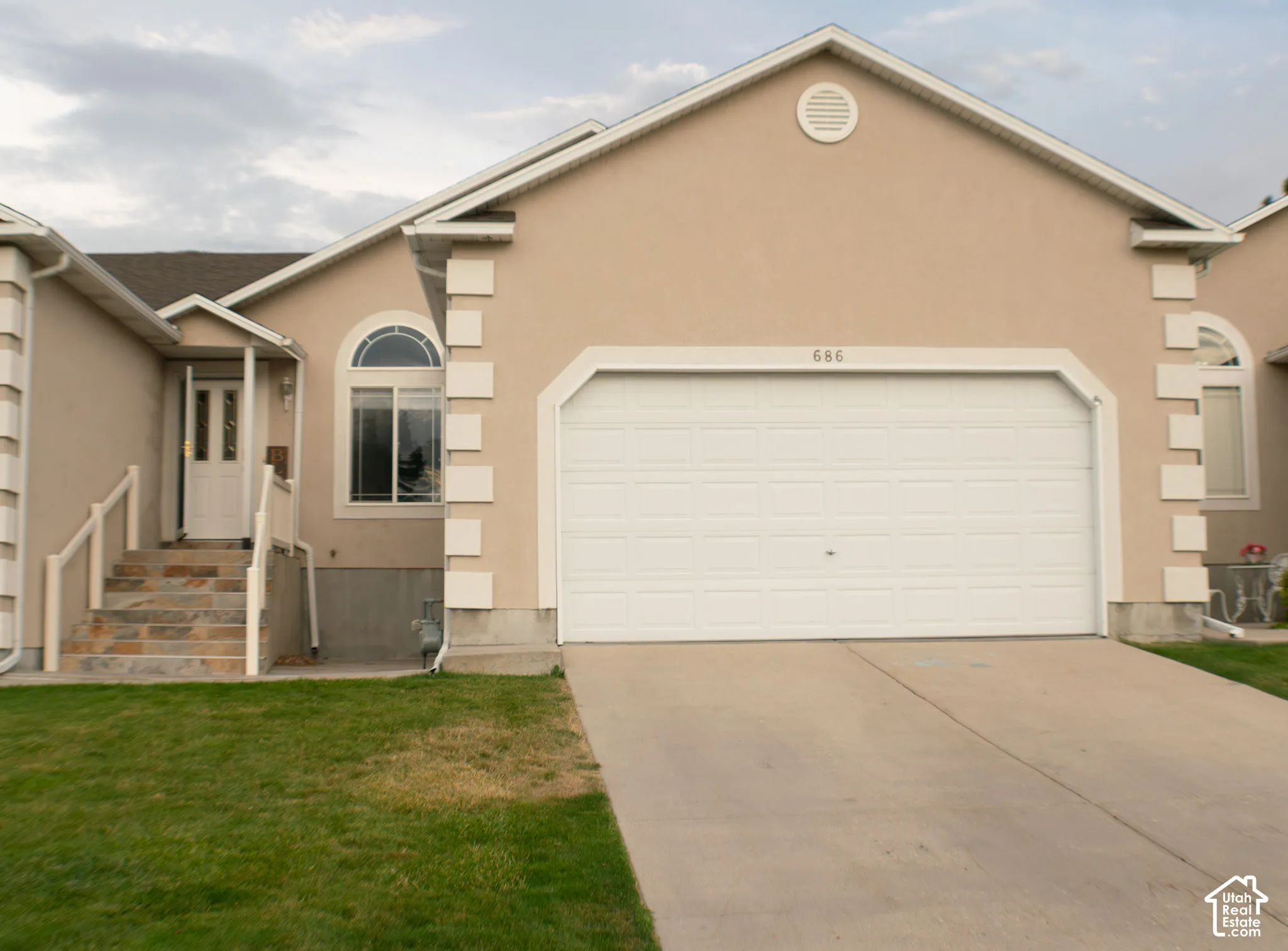 Stucco exterior with decorative trim, arched window accents, attached garage, and a concrete driveway.Custom tiled stairs