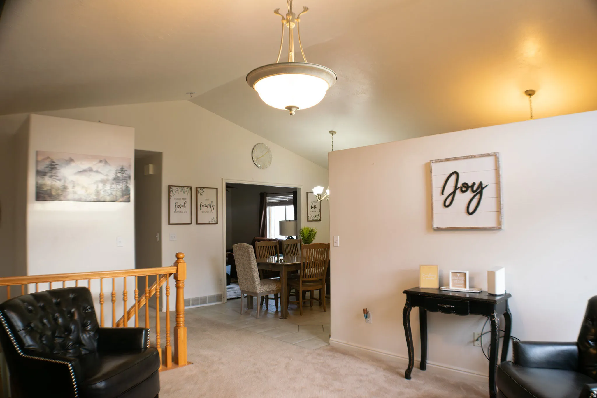 Vaulted ceilings, carpeted flooring, wood railing, and overhead lighting fixtures