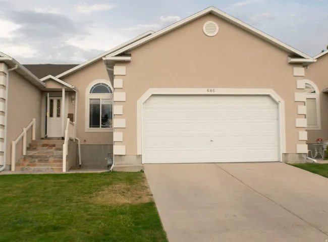 Stucco exterior with decorative trim, arched window accents, attached garage, and a concrete driveway