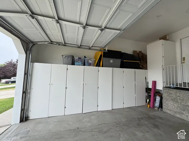 Built-in white cabinetry, concrete flooring, and an overhead garage door