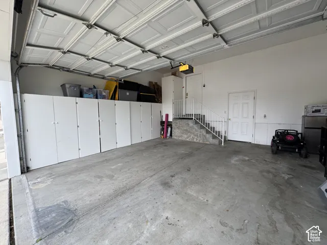 Built-in cabinetry, interior access door, concrete flooring, and an automatic garage door opener