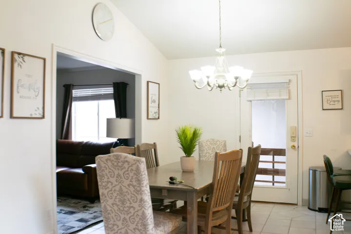 Vaulted ceilings with a chandelier light fixture above the dining area which also has a breakfast bar and provides convenient access to the outdoor patio space.