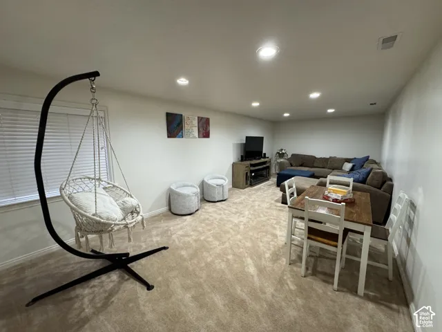 This basement family room is large enough to swing, watch movies and play games all at the same time.  It offers recessed lighting with dimmers, light-colored carpeting, and a window with horizontal blinds
