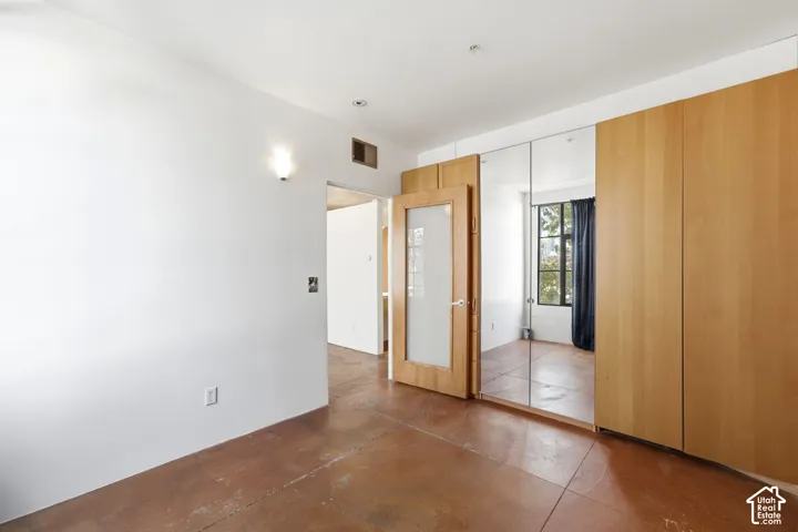 Polished concrete flooring, light wood-finish cabinetry, full-length mirrored panels, and a wood-finish door with frosted glass insert