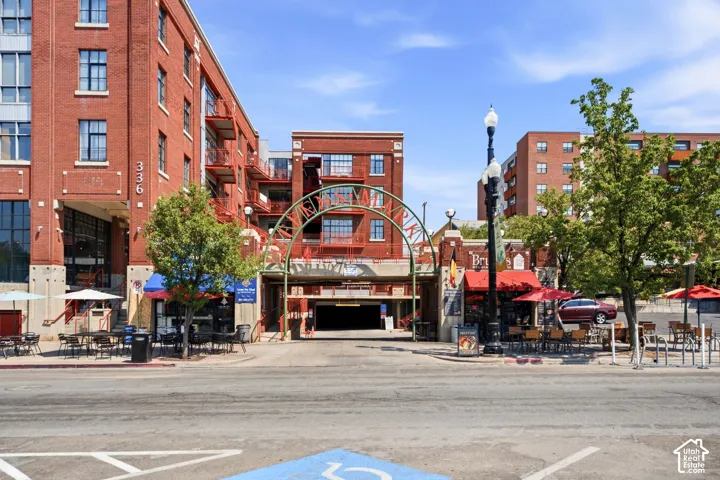 Brick facade with multiple balconies, street-level commercial spaces, and integrated multi-level parking structure