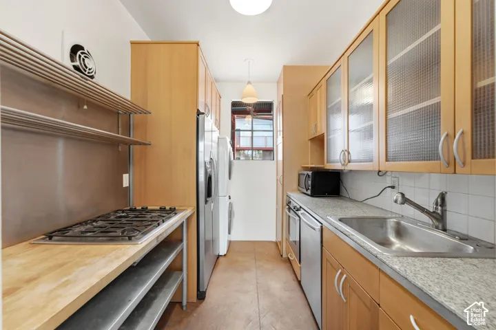 Galley kitchen with wood-finish cabinetry, stainless steel appliances, and a gas range