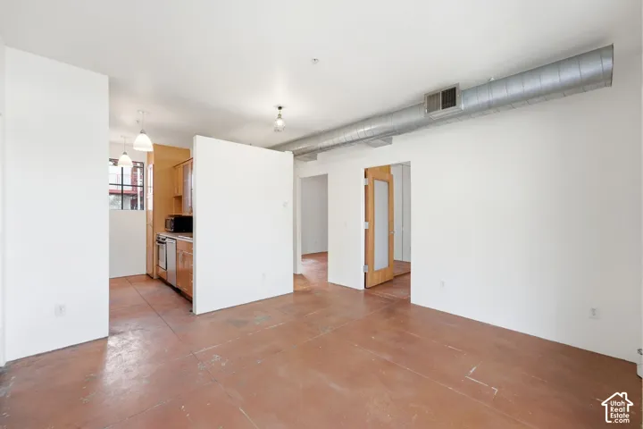 Expansive open-concept space featuring concrete flooring and exposed ductwork