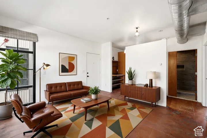 Expansive living area featuring exposed ductwork, large industrial-style windows, and polished concrete flooring