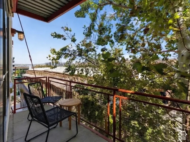 Balcony with concrete flooring, dark metal railings, and a corrugated metal ceiling
