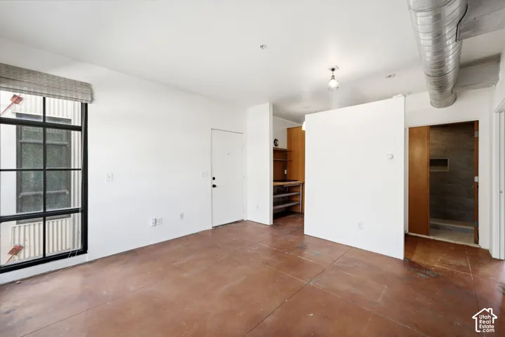 Polished concrete flooring, exposed overhead ductwork, large multi-pane window, integrated shelving, and a built-in shower niche