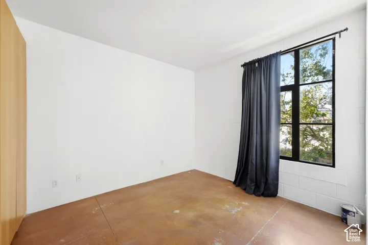 Industrial-style window with black grid, block wall construction, wood-finish wall panels, and stained concrete flooring