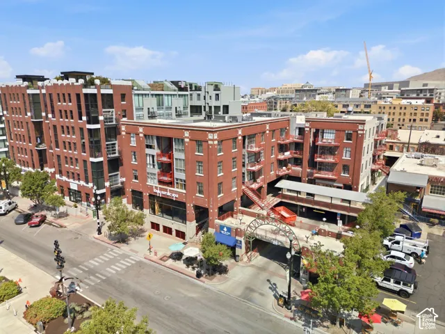 Brick facade building with multiple balconies, street-level retail, and an arched entryway leading to an interior parking structure