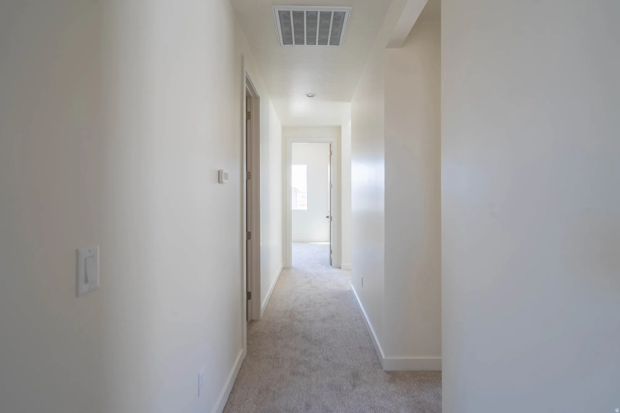 Neutral wall finishes, recessed ceiling lighting, light-toned carpeting, white trim, and a white six-panel door