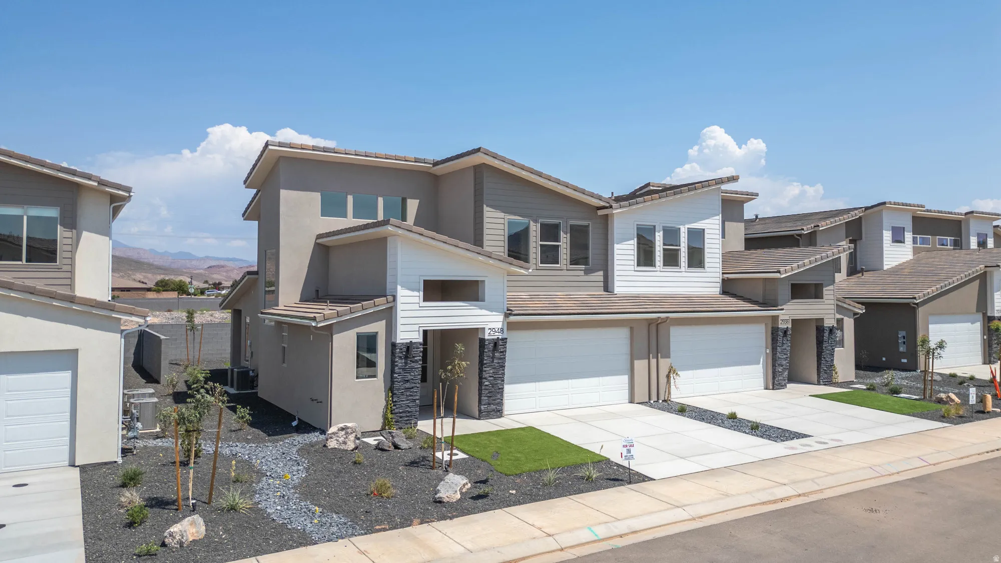 Contemporary exterior with multiple roof lines, stone accents, attached two-car garage, and a concrete driveway