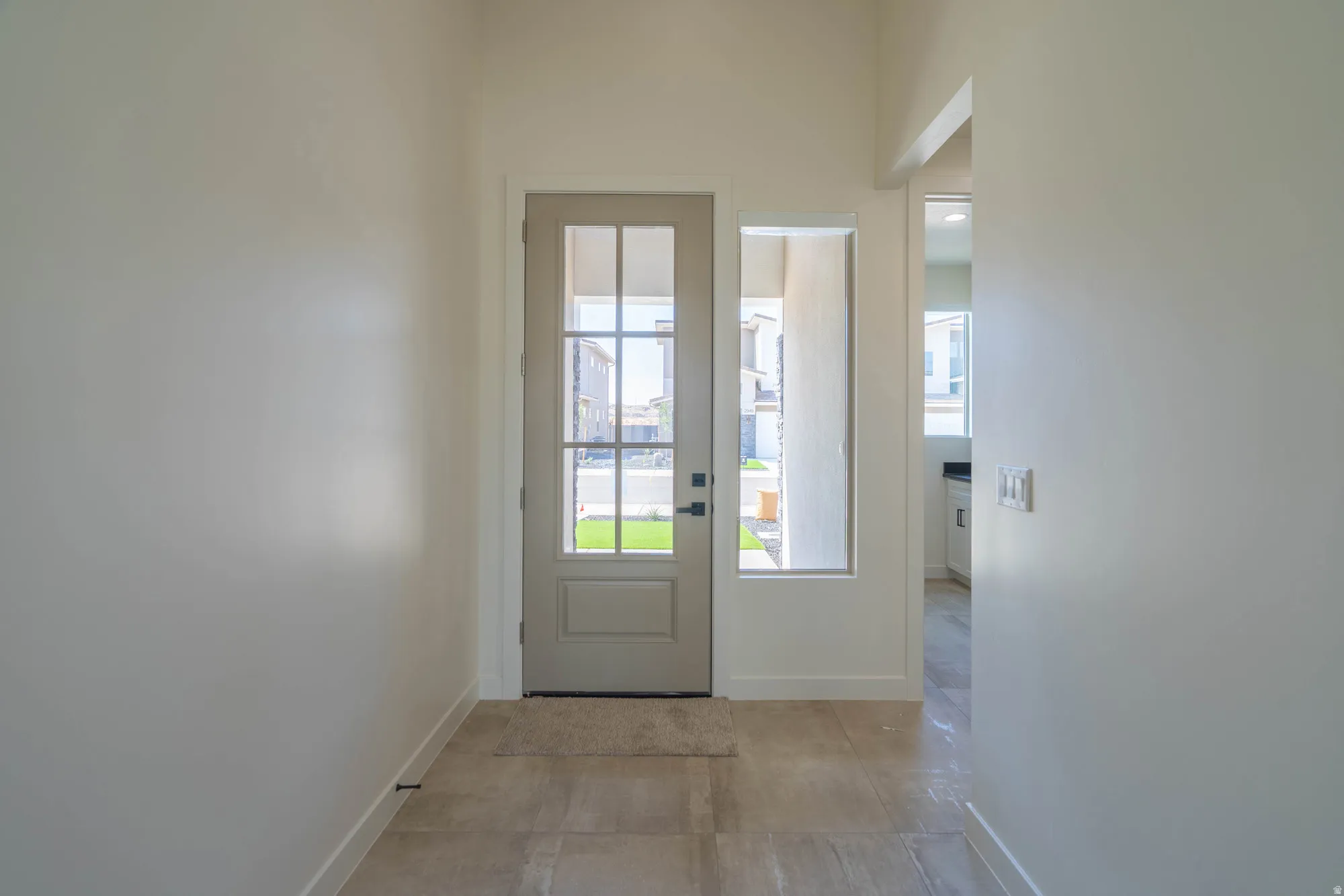 Entryway featuring a paneled door with glass inserts, an adjacent vertical window, and tile flooring