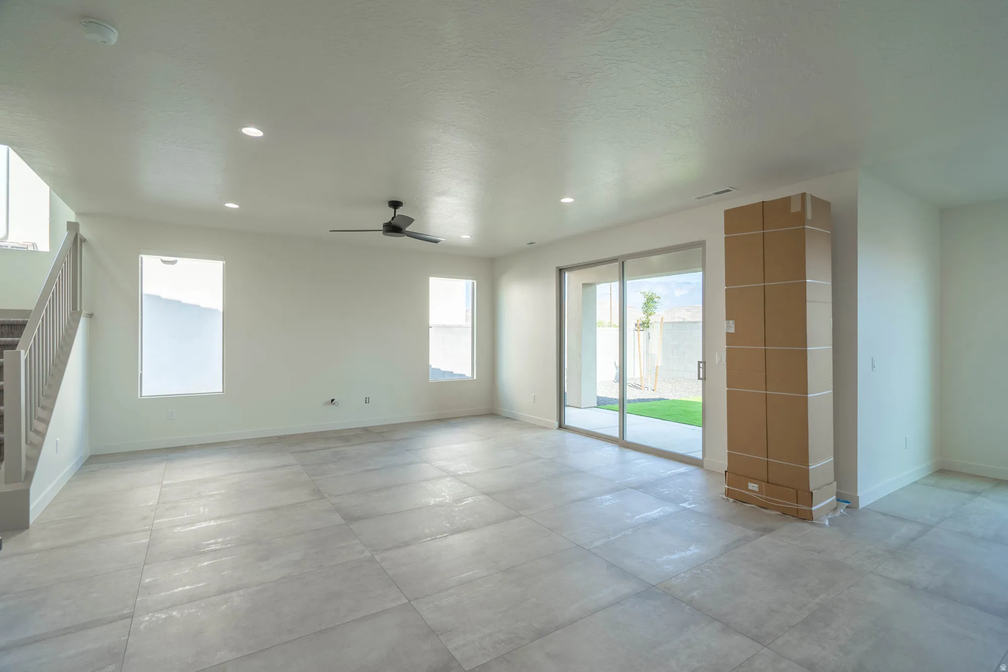 Spacious room featuring large format tile flooring, recessed lighting, and a ceiling fan