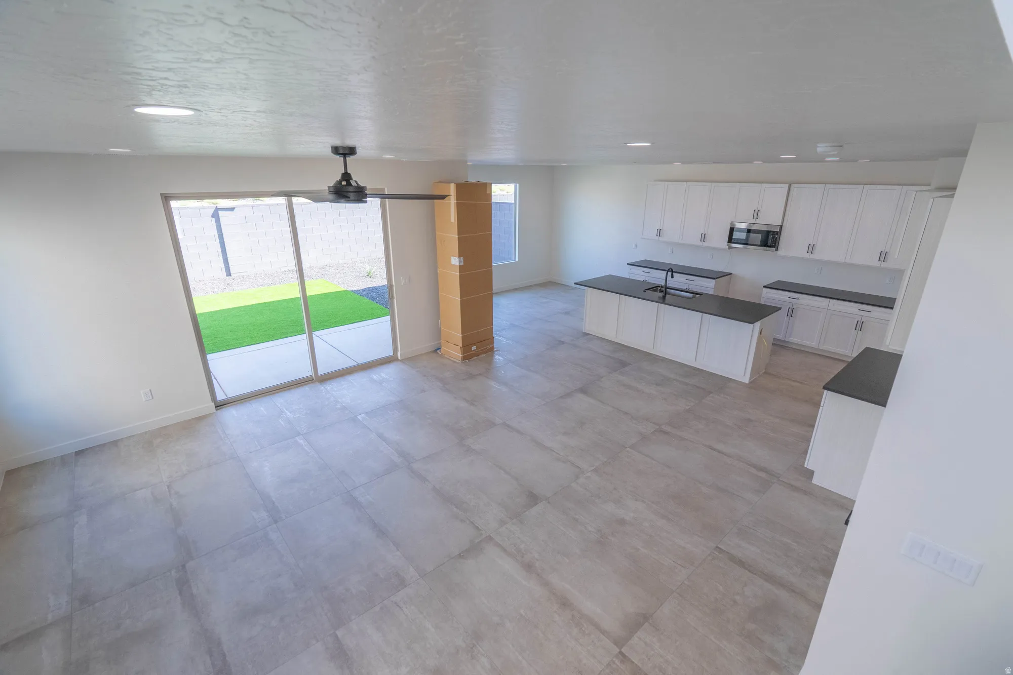 Open concept living area featuring large format floor tiling, a ceiling fan, and recessed lighting
