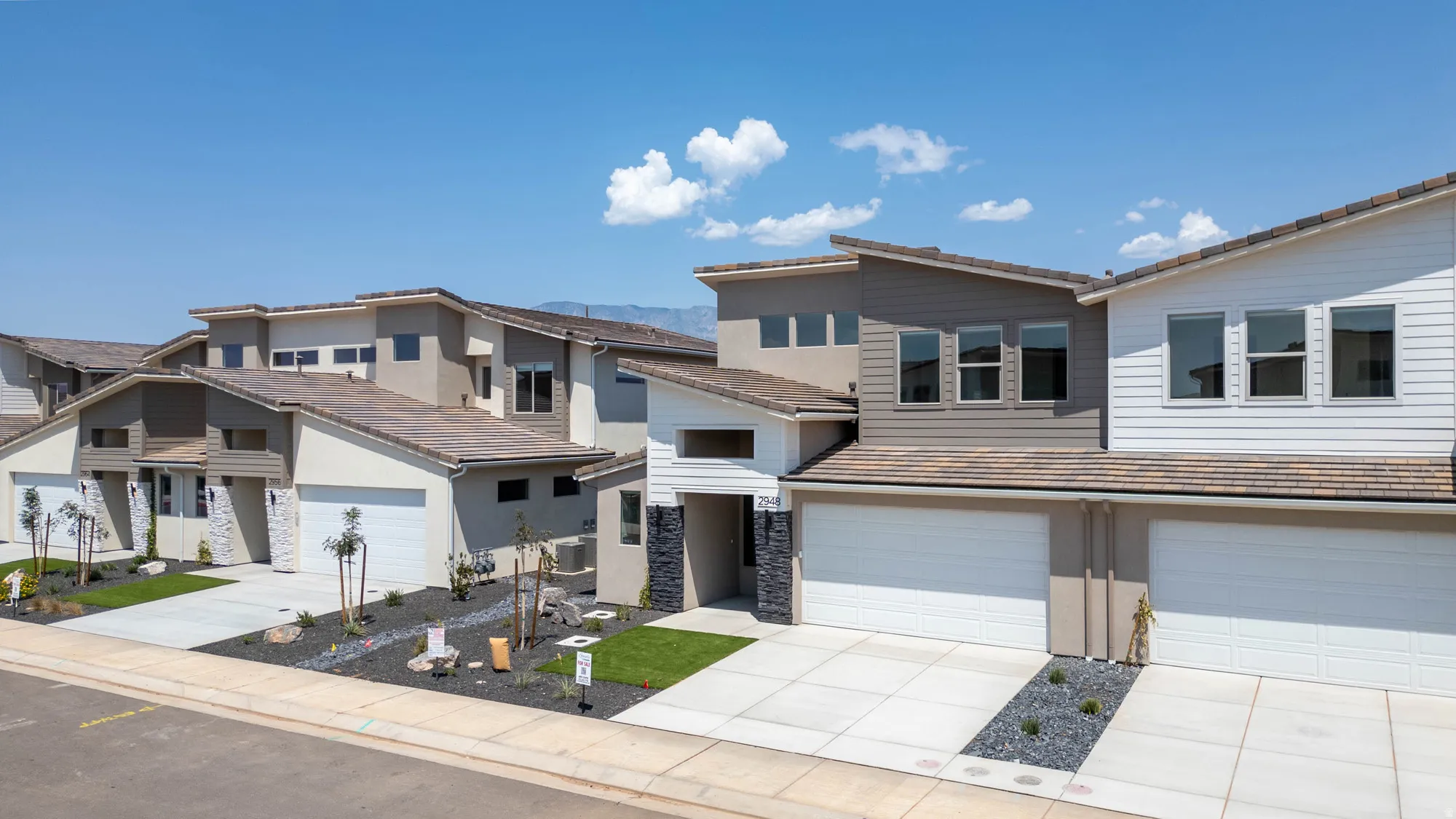Contemporary residences featuring multi-level facades, attached garages, and structured landscaping
