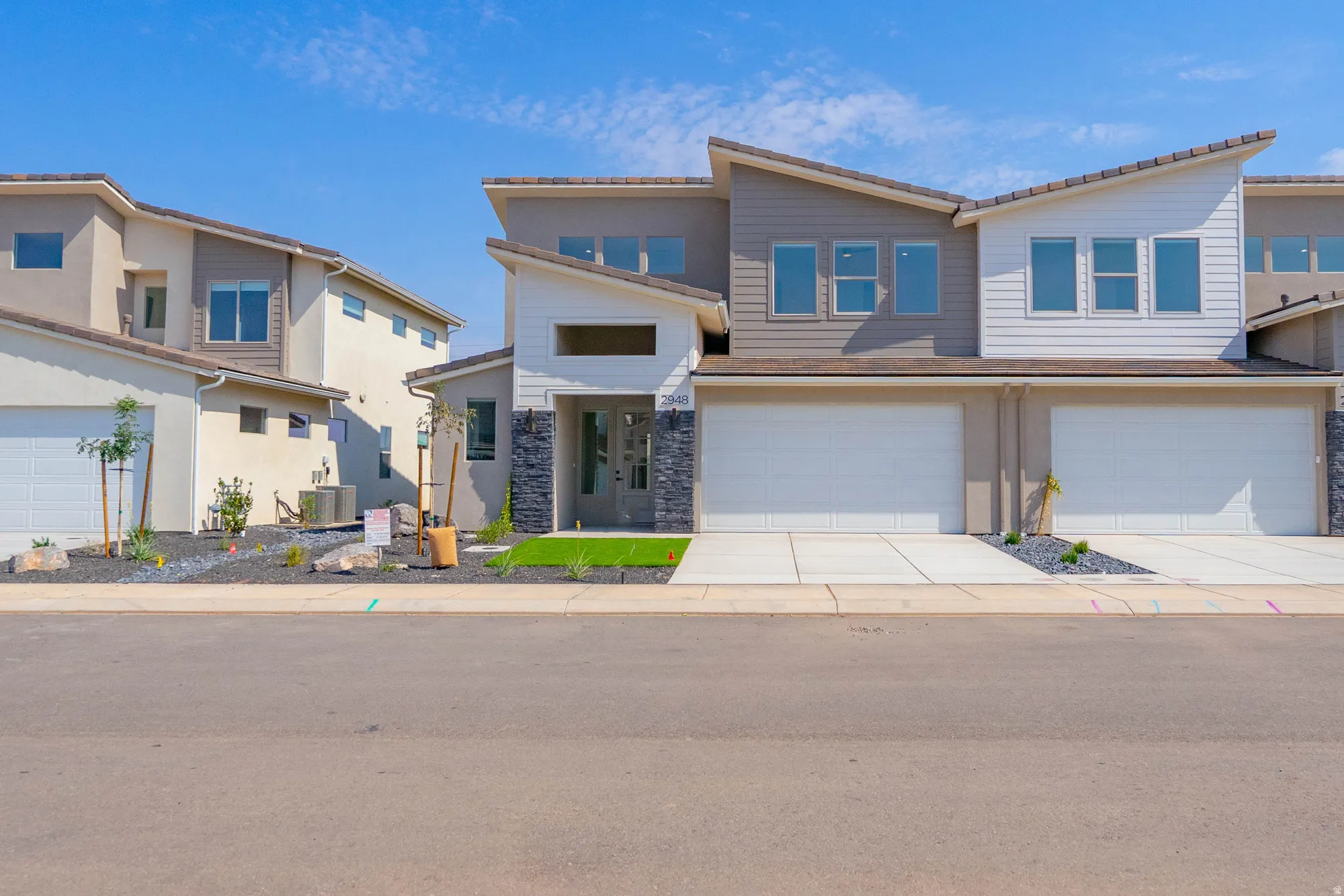 Contemporary exterior with stacked stone accents, multiple large windows, and a two-car garage