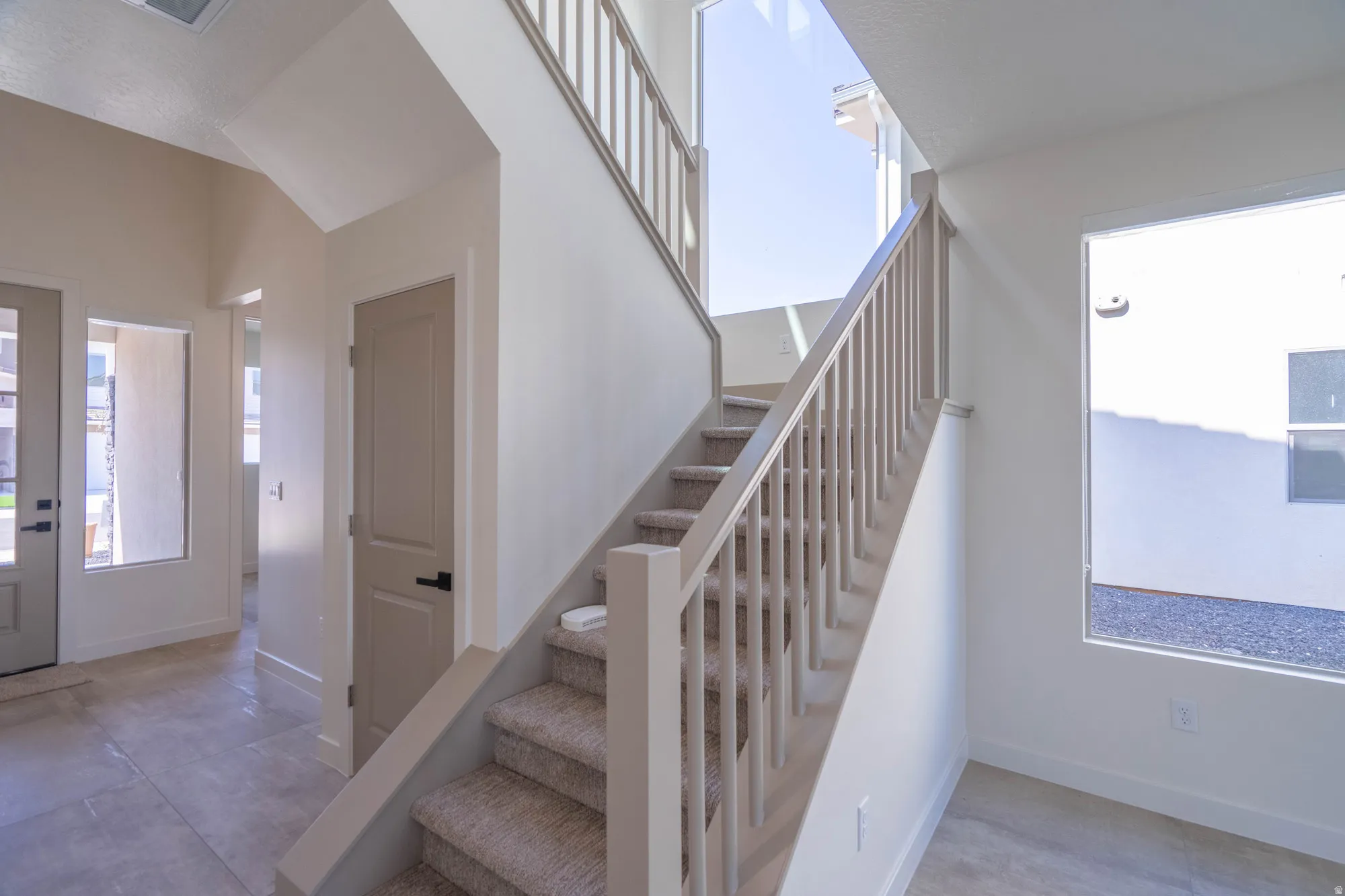 Staircase with carpeted treads and painted wood balusters