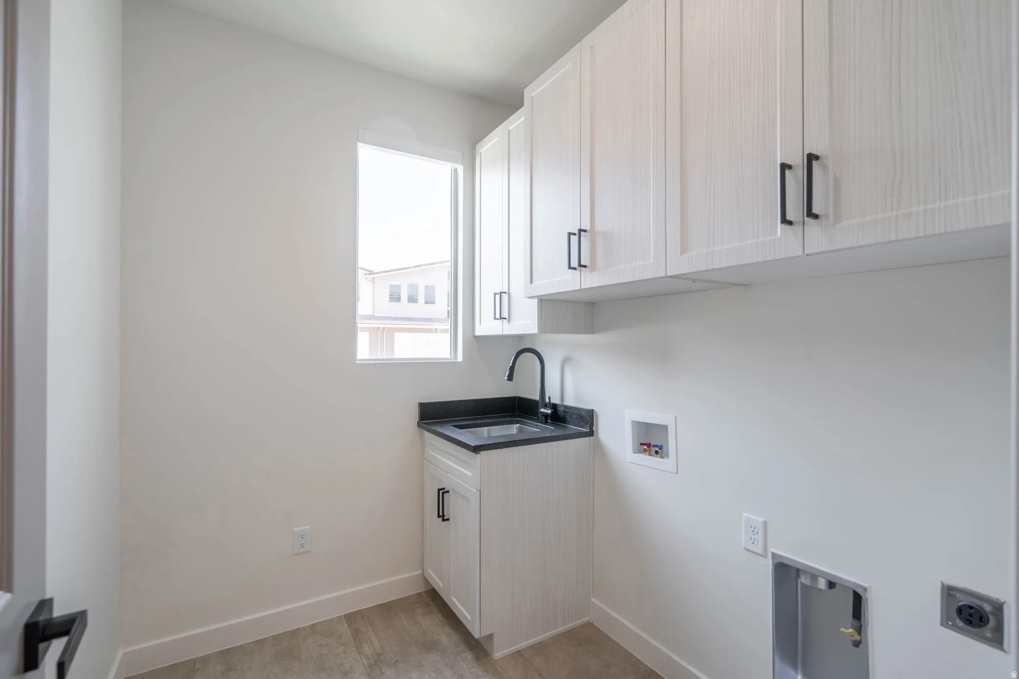 White cabinetry with matte black hardware, dark countertop with undermount sink, and matte black faucet