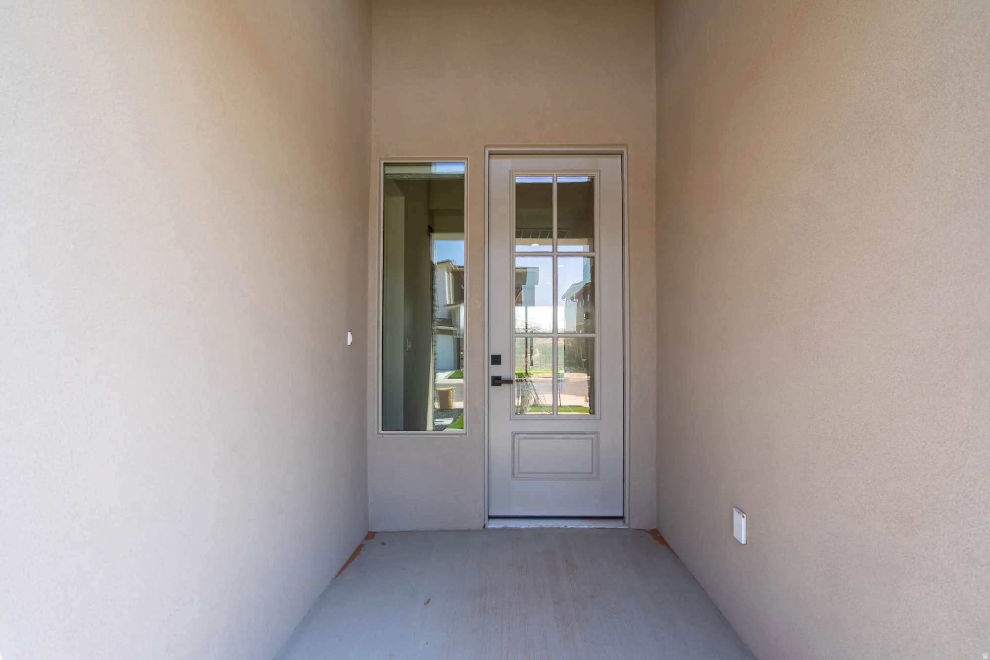 Entryway featuring a panel door with multiple glass lites, an adjacent full-length sidelight, and textured stucco walls
