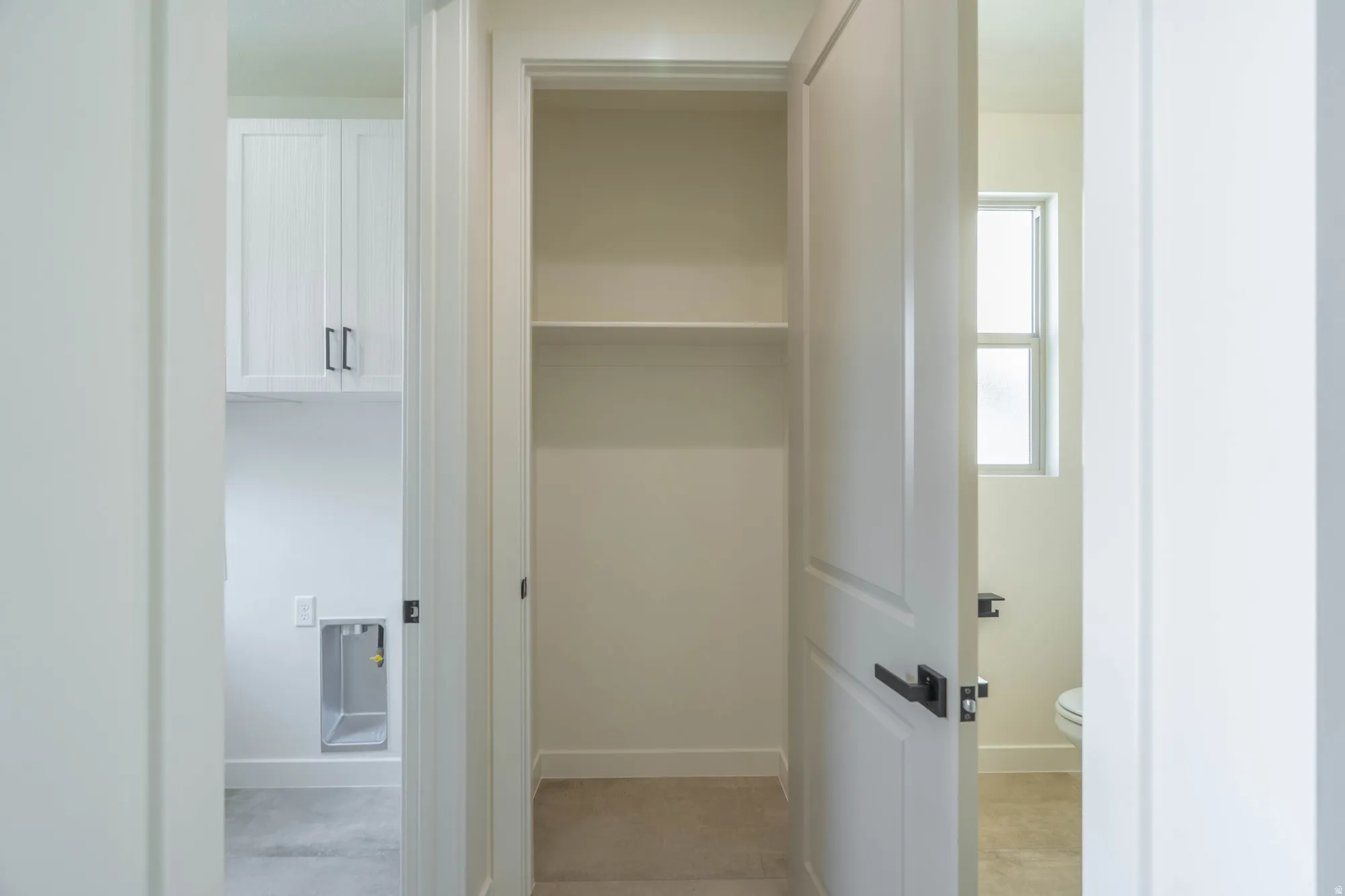 White cabinetry with dark hardware, built-in shelving, and a panel door with dark hardware